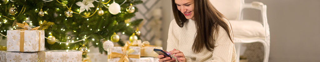 women sitting with white christmas present infront of tree boxing day sales online shopping